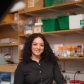 Olivia Corradin stands smiling at a lab bench.