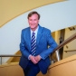 A man in a blue suit on a yellow stairwell.