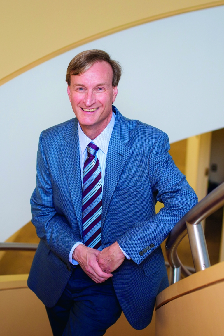 A man in a blue suit on a yellow stairwell.