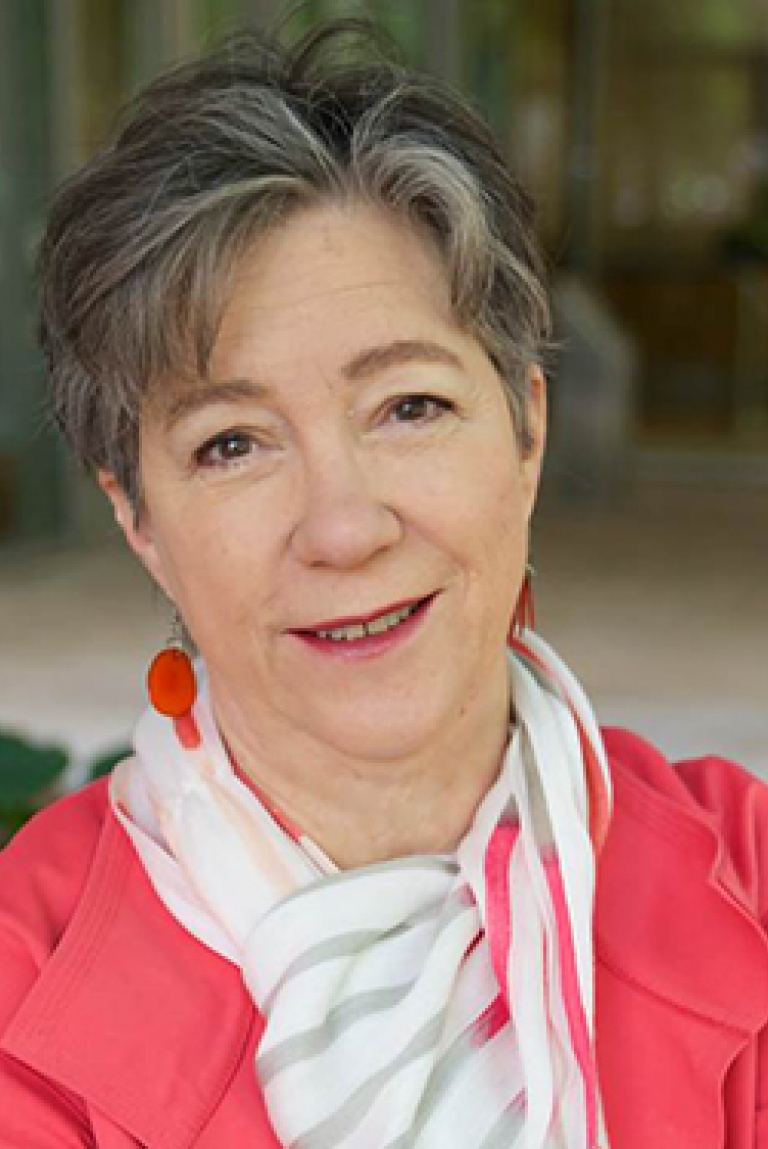 A woman with short grey hair and a pink jacket.