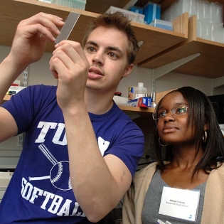 Two students look at a slide in the lab.