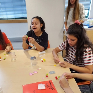 Students sit around a table with science equipment.