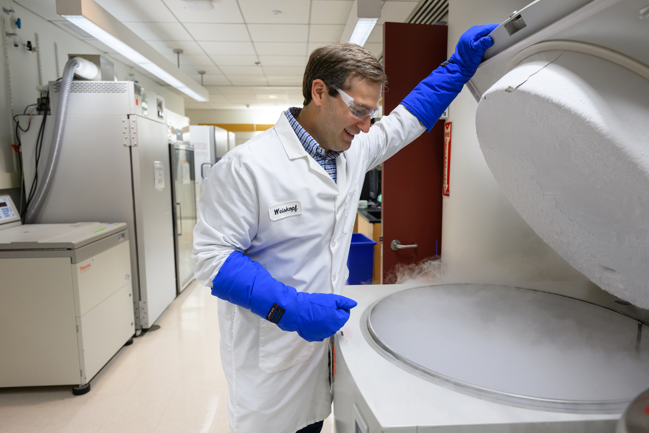 Weiskopf in lab gear and thick gloves opens a deep freezer