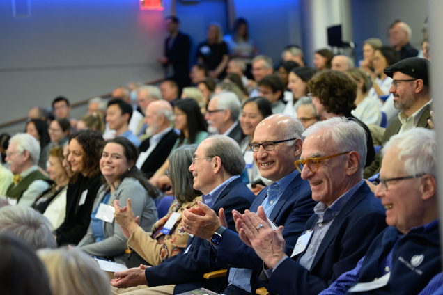 A shot of a large section of the audience smiling and clapping