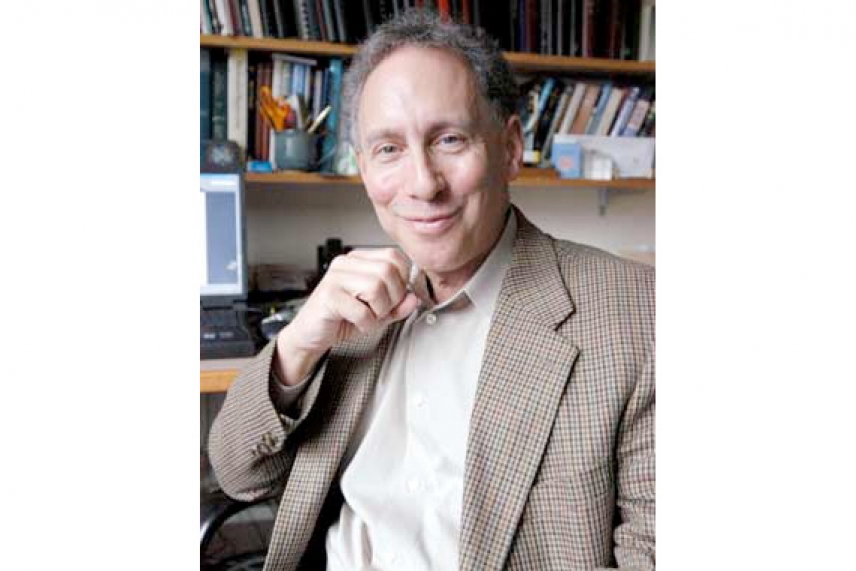 Langer in office, sitting in front of shelves of books, smiling